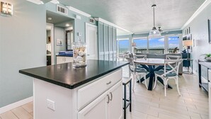 A kitchen with a central island, white cabinetry, and a view of the ocean. - Gulfstream Condos Unit 306 | Gulf Front Views & Balcony | Pool, Hot Tub (Corpus Christi)