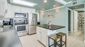 A modern kitchen with white cabinets, stainless steel appliances, and a black countertop. - Gulfstream Condos Unit 306 | Gulf Front Views & Balcony | Pool, Hot Tub (Corpus Christi)
