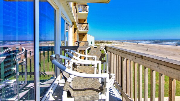 A balcony with wicker chairs, a wooden railing, and a view of the beach and ocean. - Gulfstream Condos Unit 312 | Balcony with Beach Front Views, Pool & Hot Tub (Corpus Christi)