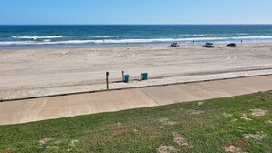 Een strand met een betonnen voetpad en een gazon.