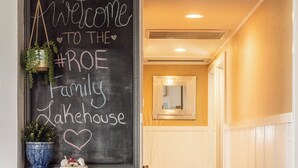 Ein Flur mit einem Kreidetafel-Schild, auf dem 'Willkommen im #ROE Family Lakehouse' steht, und einer Blumentopfpflanze links.