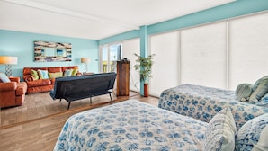 A room with a bed, a sofa, a coffee table, and a large window with blinds. - Gulfstream Condo Unit #401 Heated Pool & Hot Tub | Pickleball Court (Corpus Christi)
