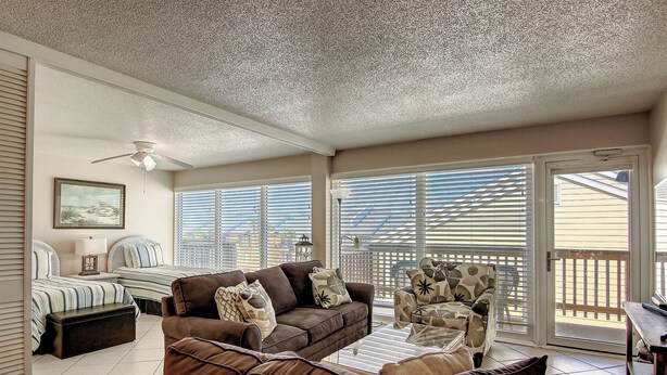 A sunroom with a ceiling fan, large windows, and a view of the outside. - Gulfstream Condos Unit 402 | Private Balcony | Pool, Hot Tub & BBQ (Corpus Christi)