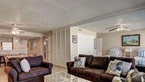 A living room with two brown leather sofas, a glass coffee table, and a ceiling fan. - Gulfstream Condos Unit 402 | Private Balcony | Pool, Hot Tub & BBQ (Corpus Christi)