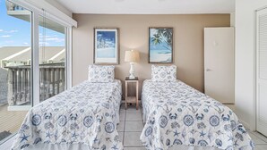 A room with two beds, a ceiling fan, and a view of the ocean through large sliding glass doors. - Unit 403 Private Balcony/Heated Pool & Hot Tub / BBQ (Corpus Christi)