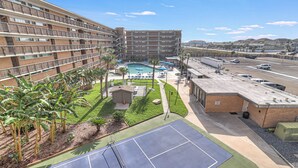 A multi-story hotel with a rooftop pool, tennis court, and a parking area. - Unit 403 Private Balcony/Heated Pool & Hot Tub / BBQ (Corpus Christi)