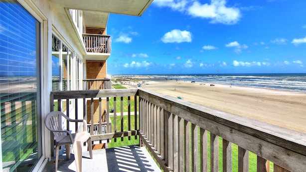 A balcony with a view of the beach and ocean.