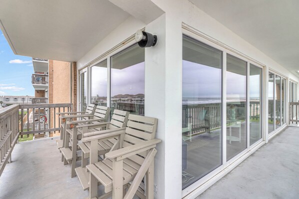 A balcony with wooden chairs and a camera on the wall, overlooking a residential area.