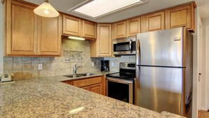 Una cocina con armarios de madera, encimeras de granito, electrodomésticos de acero inoxidable y un tragaluz.