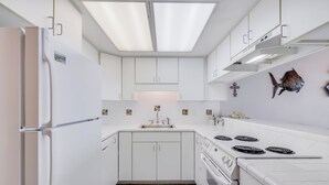 Une cuisine moderne avec des meubles blancs, une cuisinière encastrée et une grande fenêtre.