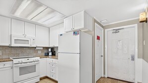 A kitchen with white cabinets, a microwave, a refrigerator, a stove, and a tiled floor. - Gulfstream Condos Unit 508 | Gulf Views & Beachfront Balcony | Pool, Hot Tub (Corpus Christi)