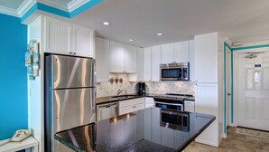A modern kitchen with white cabinets, stainless steel appliances, and a granite countertop. - GSC Unit 512 | Pickleball, Pool, Hot Tub & BBQ | Beachfront View (Corpus Christi)