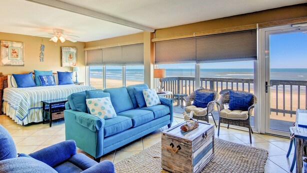 Une chambre avec un lit, un canapé bleu et une vue sur la plage.