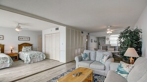 Ein geräumiges Wohnzimmer mit einer Couch, einem Couchtisch und einem Bett mit gemusterten Betttextilien.