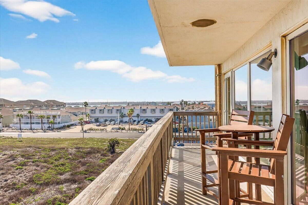 Un balcone con vista su una cittadina costiera, arredi in legno e cielo sereno.
