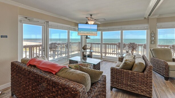 Ein geräumiger Balkon mit Blick auf den Strand, ausgestattet mit Korbsesseln und einem Fernseher.