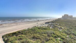 Vista costera con playa, carretera y un edificio a lo lejos.