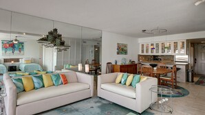 En moderne stue med sofa, stole, spisebord og et køkkenområde.
