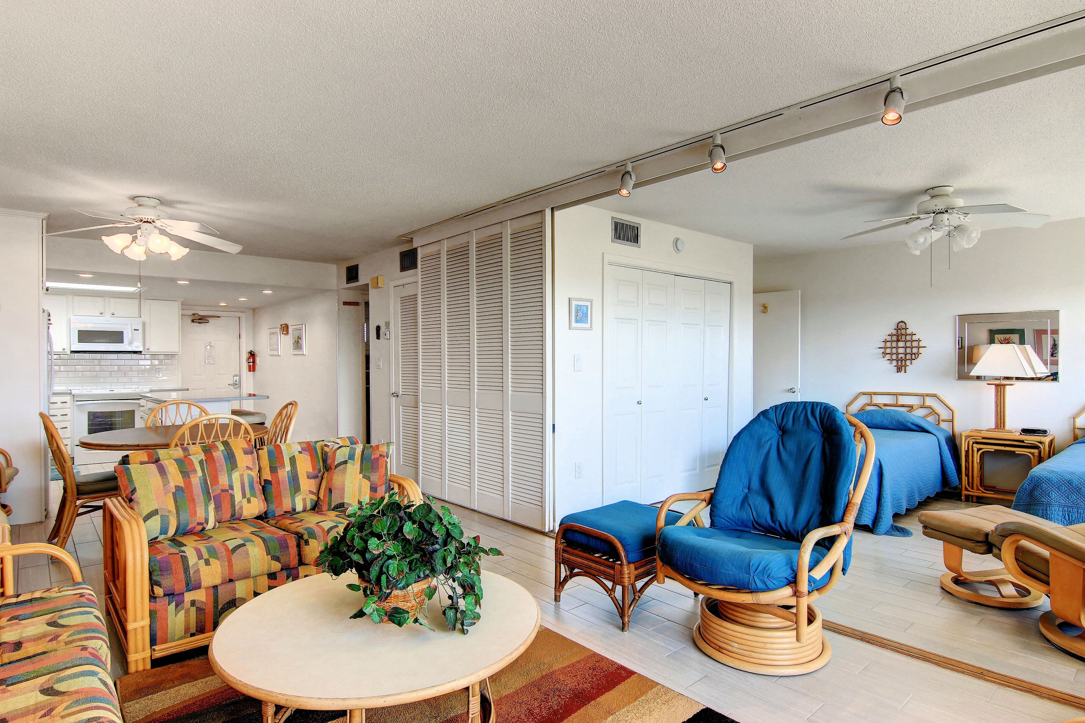 A living room with a sofa, chairs, a table, and a ceiling fan.