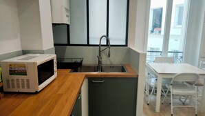 Une cuisine de taille réduite équipée d’un four à micro-ondes, d’un évier et d’un plan de travail en bois.