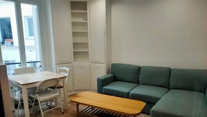Une pièce comprenant une table à manger, des chaises, un banc, un canapé vert et une armoire blanche.