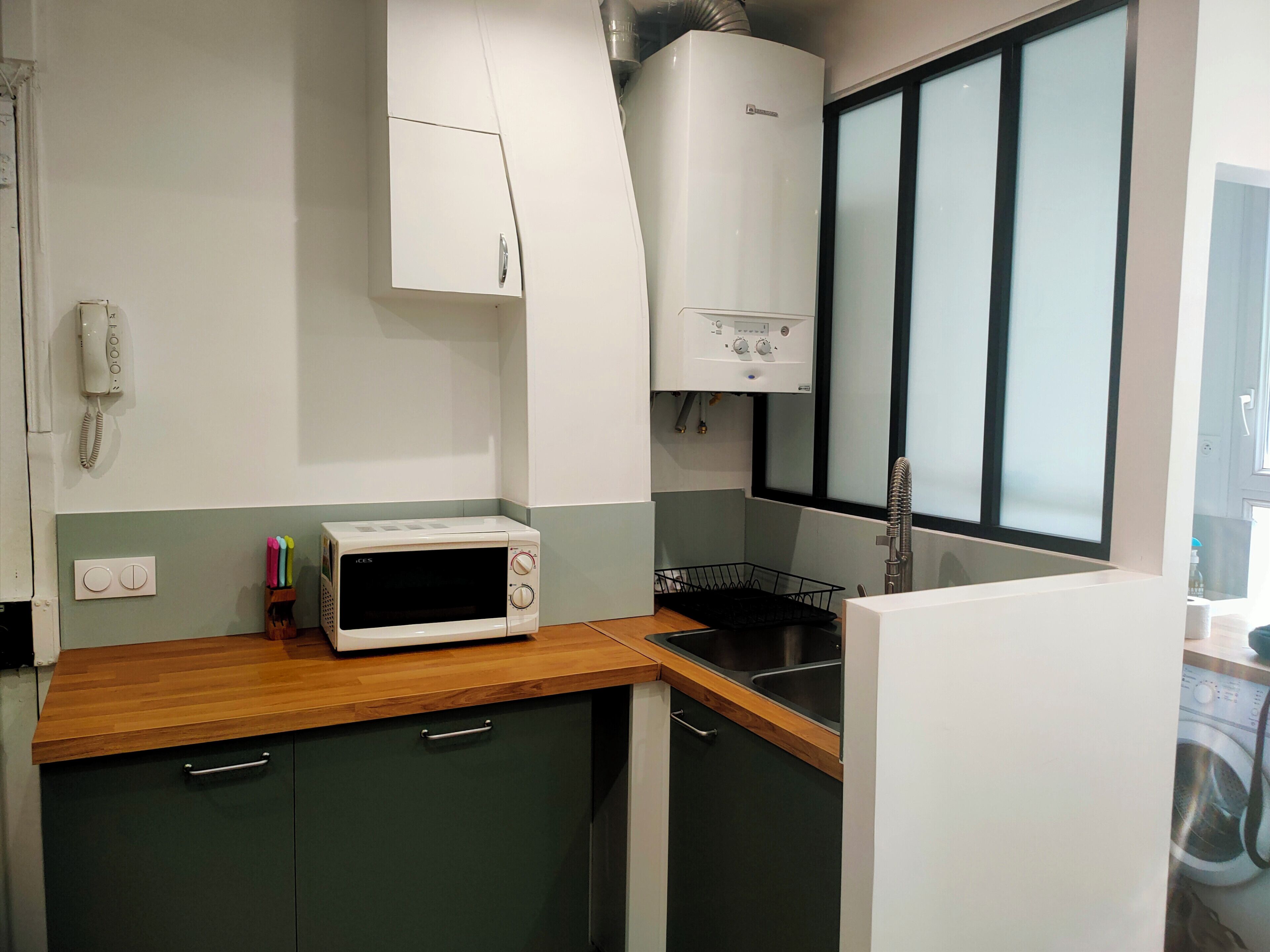 A compact kitchen with a microwave, a sink, and cabinets.