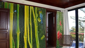 Una habitación con un gran mural con motivos de bambú, una puerta de madera y vistas a través de un ventanal.