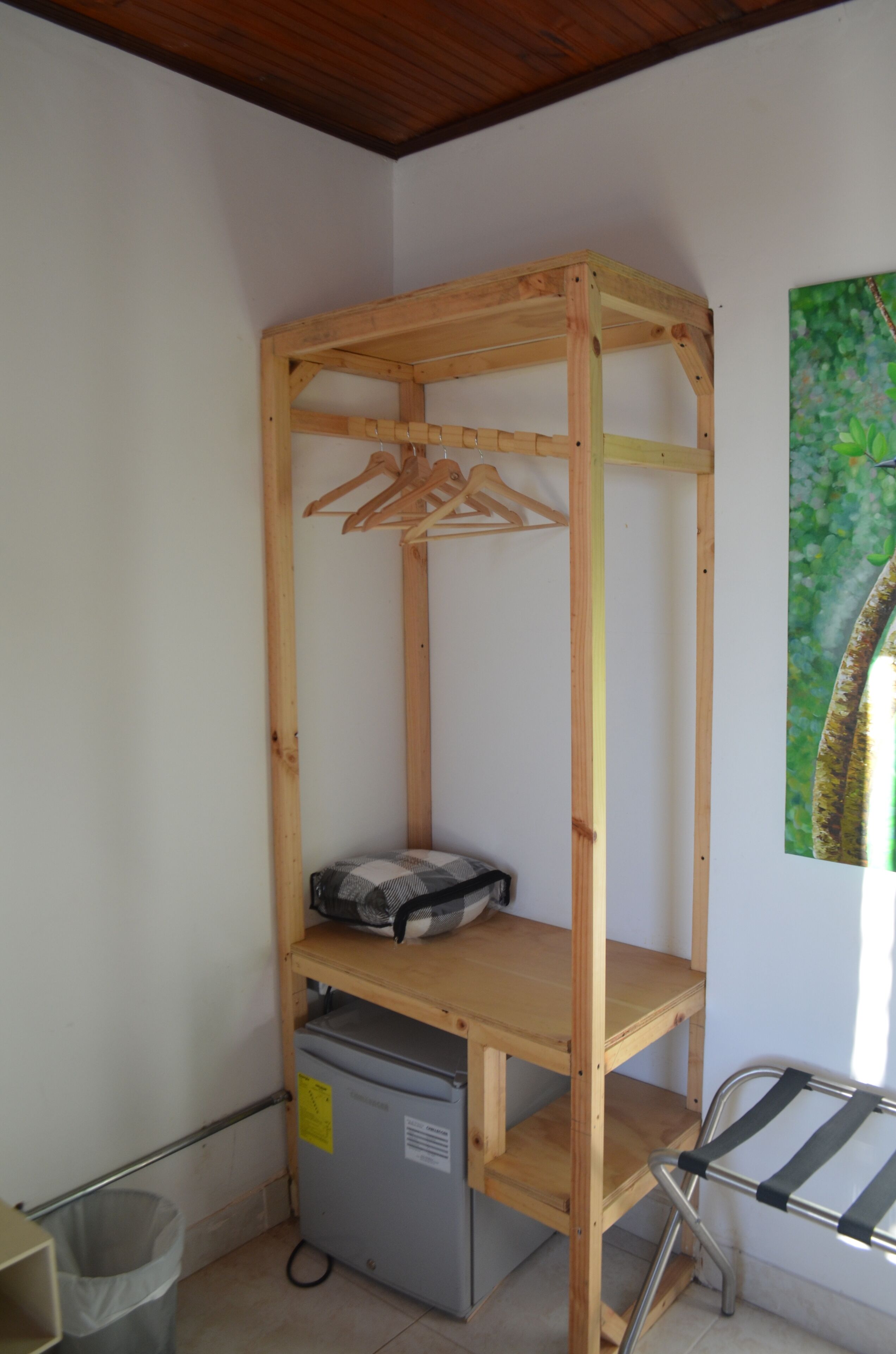 A room with a wooden bunk bed, a small desk, a grey storage unit, and a metal drying rack.