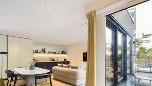 A modern interior with a dining area, sofa, and a view of the outside. - Be London - The St Pancras Residences (London)