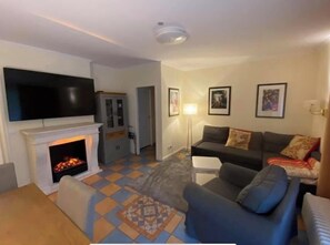 Una sala de estar con chimenea, un televisor de pantalla plana montado en la pared, un sofá y un tapete estampado.