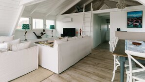 A spacious loft-style living area with a high ceiling, white walls, and a wooden floor. - Seehütte Sonnenschilf (Rust)
