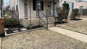 Una casa de un solo piso con porche delantero, un pequeño jardín frontal y una escalera visible que conduce a la entrada.