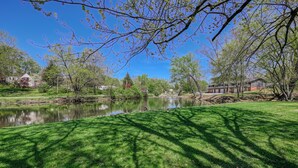 Una vista serena d'un llac amb un jardí ben cuidat, un estany tranquil i diversos arbres.