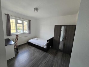 Cozy retreat with a single bed, dark wood wardrobe, and desk area.
