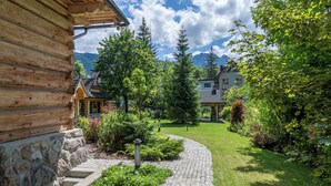 A log cabin with a stone foundation, surrounded by a well-maintained garden and a cobblestone pathway. - Willa Elżbiecina (Zakopane)