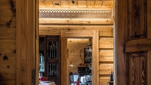 A wooden interior with a dining area, including a table and chairs, and a large wooden door. - Willa Elżbiecina (Zakopane)