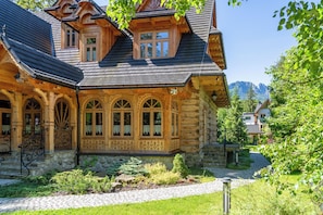 A wooden house with a stone foundation, a stone pathway, and a mountain view in the background. - Willa Elżbiecina (Zakopane)