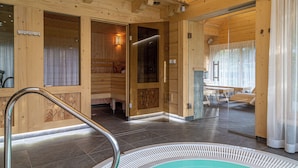 A wooden spa room with a hot tub, wooden walls, and a glass door leading to a seating area. - Willa Elżbiecina (Zakopane)