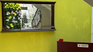 A reception area with a sign reading 'RESEPSİYON RECEPTION,' a window with flowers, a bench, and a stone floor. - Lokal Ayvalık (Ayvalik)