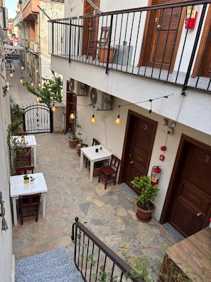 A courtyard with a table and chairs, potted plants, and a fire extinguisher. - Lokal Ayvalık (Ayvalik)