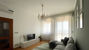 Ein modernes Wohnzimmer mit Flachbildfernseher, grauem Sofa und einer Kronleuchter.