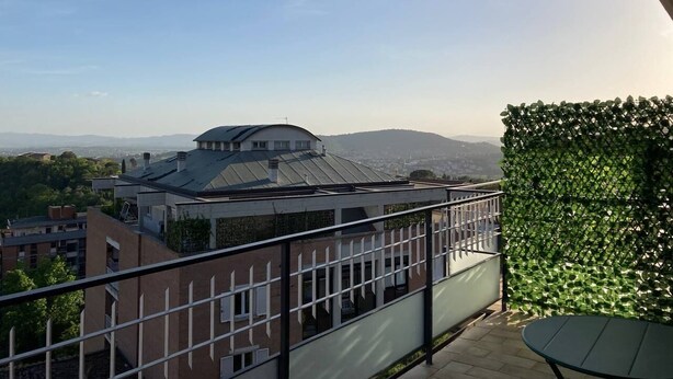 Ein Balkon mit Blick auf ein Gebäude mit Kuppel und einer Grünwand.
