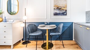 Een moderne keuken met een ronde tafel, twee stoelen, een spiegel en een schilderij aan de muur.