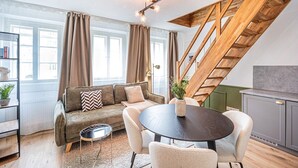 En moderne stue med sofa, rundt bord og trappe.