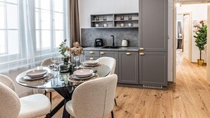 A modern kitchen with grey cabinets, a dining table with chairs, and a coffee machine.