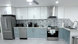Una cocina moderna con ventilador de techo, electrodomésticos de acero inoxidable y armarios de colores claros.