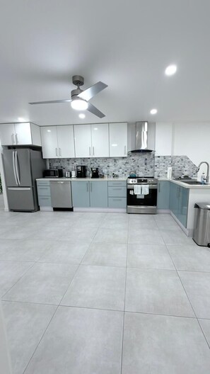 A modern kitchen with a ceiling fan, stainless steel appliances, and light-colored cabinets. - Sunset on the ocean (Bethel)