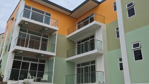Un edificio residencial de varios pisos con balcones, ventanas amplias y techo plano.