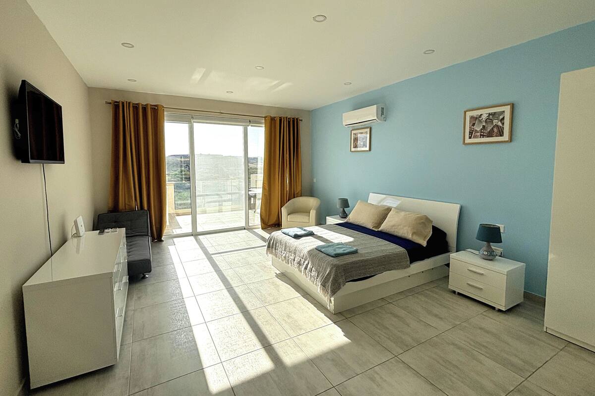 A modern hotel room with a bed, bedside tables, a desk, and a TV.