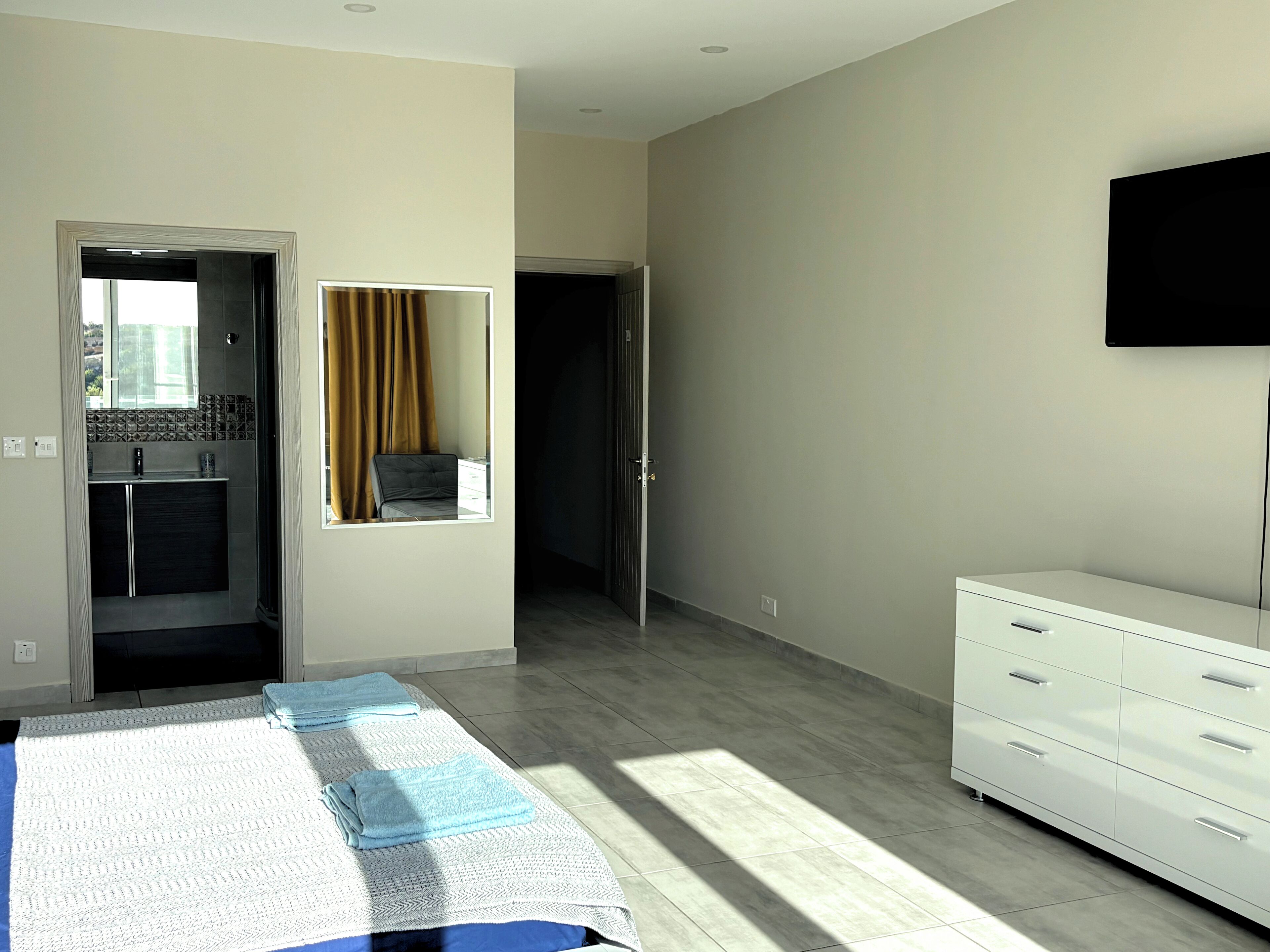A modern bedroom with a bed, a wardrobe, a mirror, and a television.